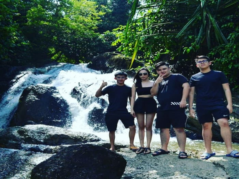 Tourists posing in front of a waterfall at ATV Adventure Ride Langkawi